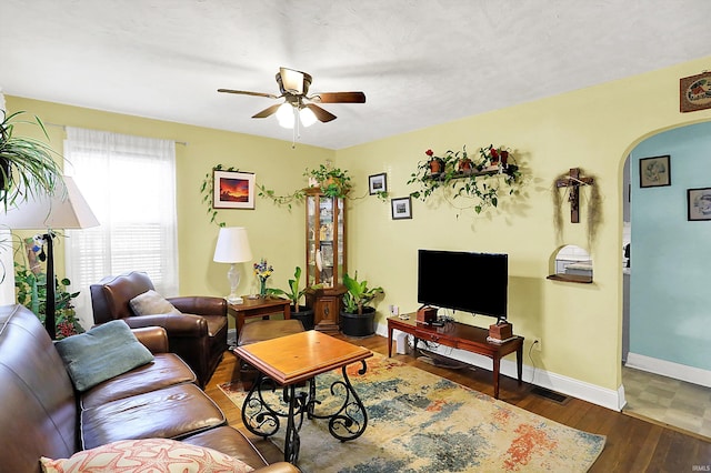 living room with baseboards, arched walkways, visible vents, ceiling fan, and wood finished floors
