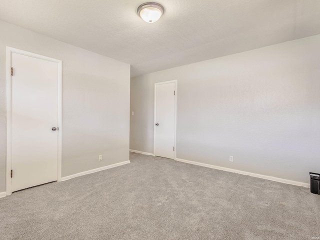 empty room featuring carpet and baseboards