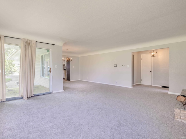 unfurnished living room with a chandelier, light colored carpet, and baseboards