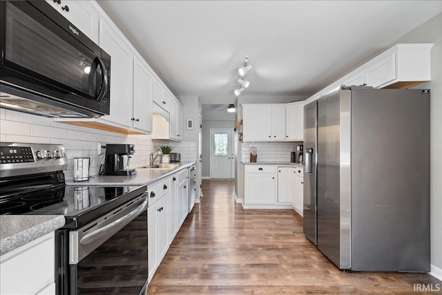 kitchen with a sink, a ceiling fan, white cabinetry, wood finished floors, and stainless steel appliances