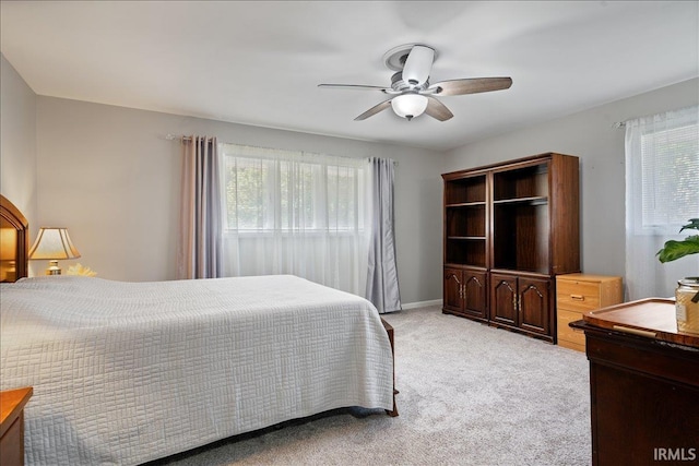 bedroom featuring baseboards, multiple windows, a ceiling fan, and light carpet