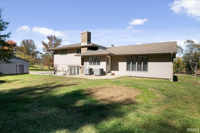 back of house with a lawn, a chimney, central AC unit, and a patio area