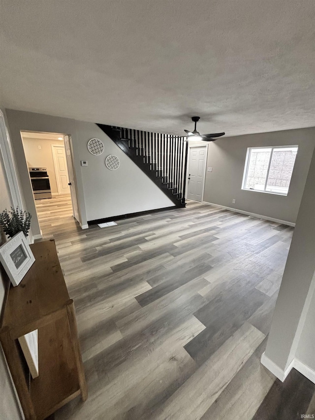 309 E S St, Eaton, IN 47338 - unfurnished living room featuring baseboards, ceiling fan, wood finished floors, a textured ceiling, and stairway