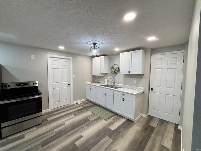 309 E S St, Eaton, IN 47338 - kitchen with electric stove, a sink, recessed lighting, white cabinets, and light wood-style flooring