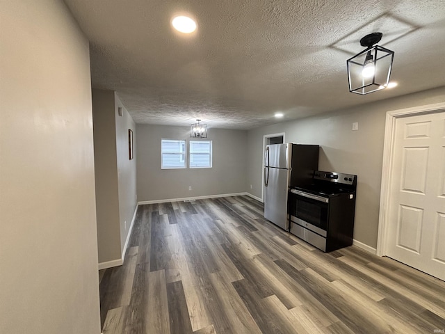 309 E S St, Eaton, IN 47338 - kitchen featuring appliances with stainless steel finishes, dark wood-style floors, baseboards, a textured ceiling, and a chandelier