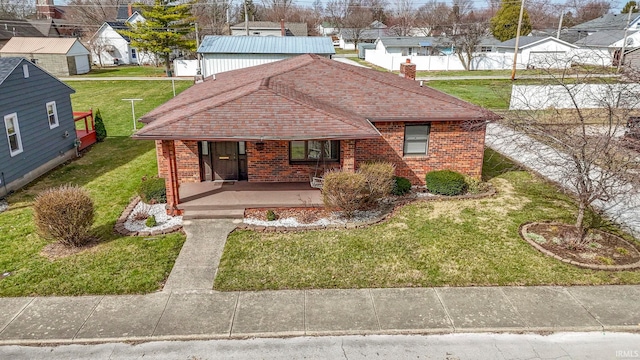 416 Maple St, Tipton, IN 46072 - view of front of home with brick siding, a front lawn, roof with shingles, and a residential view