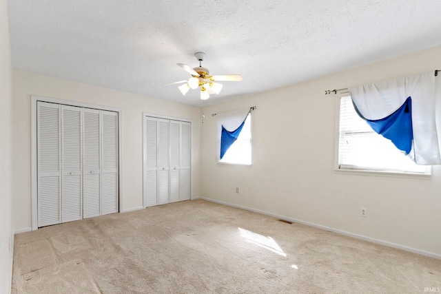 416 Maple St, Tipton, IN 46072 - unfurnished bedroom with a textured ceiling, visible vents, two closets, ceiling fan, and carpet floors