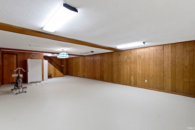 416 Maple St, Tipton, IN 46072 - finished below grade area featuring a textured ceiling, visible vents, wood walls, freestanding refrigerator, and light colored carpet