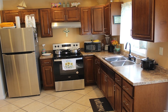 kitchen with light countertops, a sink, appliances with stainless steel finishes, under cabinet range hood, and light tile patterned floors