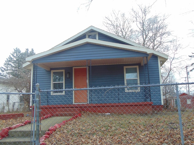 bungalow with covered porch, a fenced front yard, and a gate