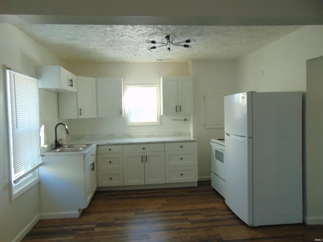 kitchen featuring white appliances, dark wood-style flooring, a textured ceiling, a sink, and white cabinets