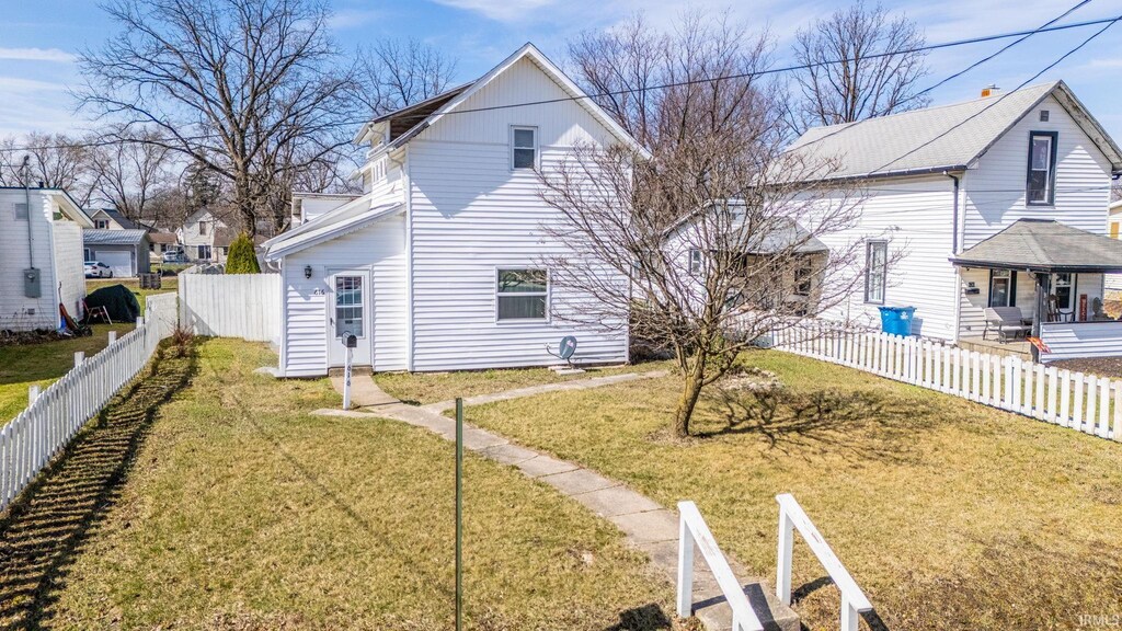 back of property with a fenced backyard and a lawn