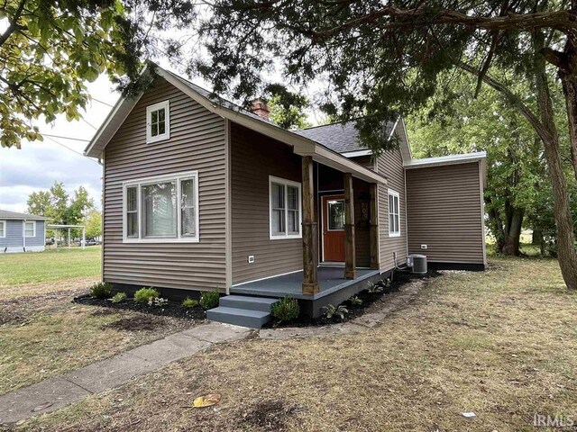 view of front of house with a front yard, central air condition unit, and a chimney