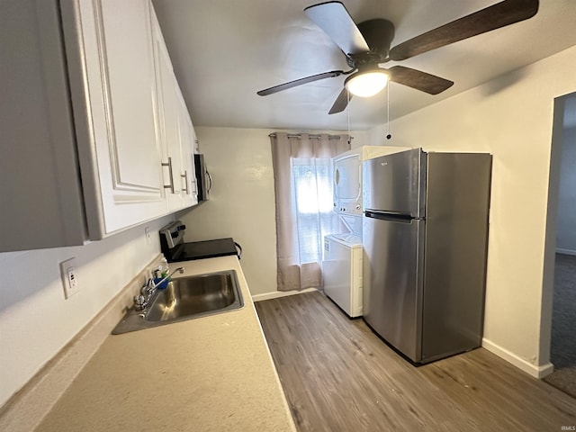 112 W Bond St, Attica, IN 47918 - kitchen featuring white cabinets, stacked washer / dryer, wood finished floors, stainless steel appliances, and a sink