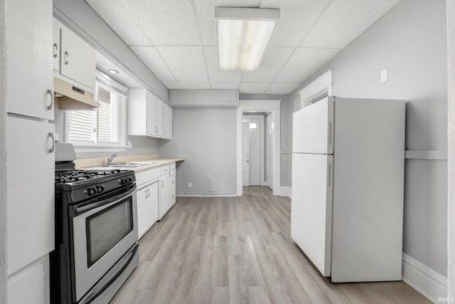 kitchen with white cabinets, light wood finished floors, under cabinet range hood, gas range, and freestanding refrigerator