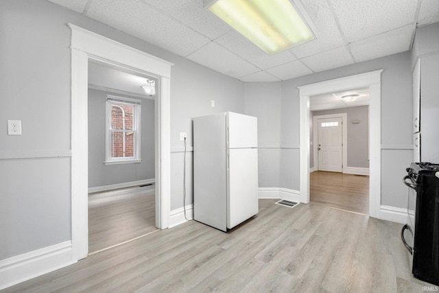 kitchen with visible vents, light wood-style floors, a paneled ceiling, black gas range, and freestanding refrigerator