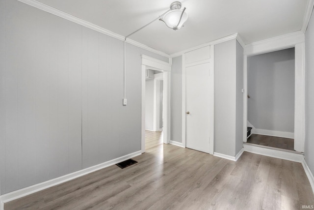 unfurnished bedroom featuring baseboards, visible vents, crown molding, and wood finished floors