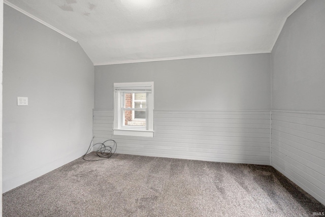 empty room with carpet floors, vaulted ceiling, and crown molding