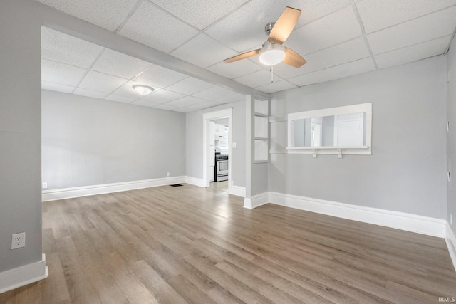 unfurnished living room with baseboards, wood finished floors, ceiling fan, and a paneled ceiling
