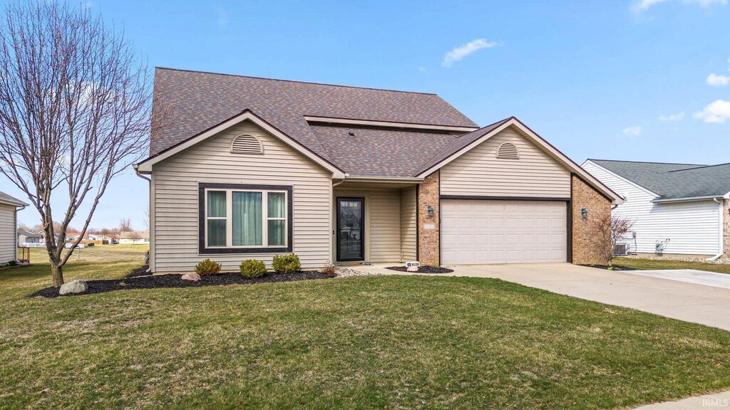 view of front of home featuring driveway, brick siding, a front lawn, a shingled roof, and a garage