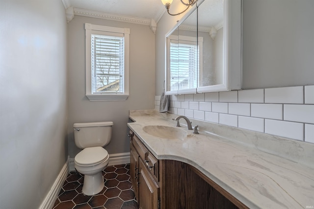 bathroom featuring crown molding, toilet, vanity, baseboards, and decorative backsplash