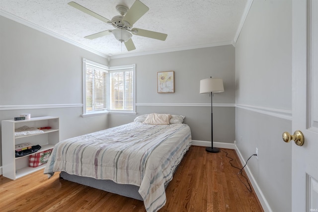 bedroom featuring ornamental molding, baseboards, a textured ceiling, a ceiling fan, and wood finished floors