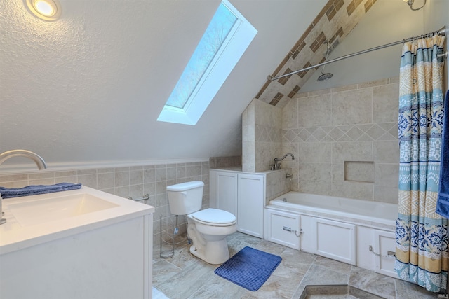 bathroom featuring tile walls, toilet, vanity, shower / tub combo with curtain, and lofted ceiling with skylight