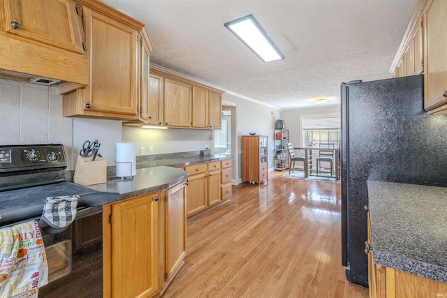 kitchen featuring a textured ceiling, light wood-style flooring, ornamental molding, dark countertops, and black appliances