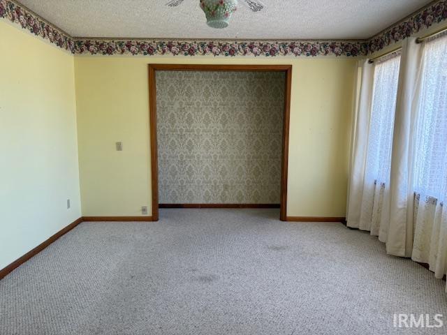 carpeted spare room with baseboards and a textured ceiling