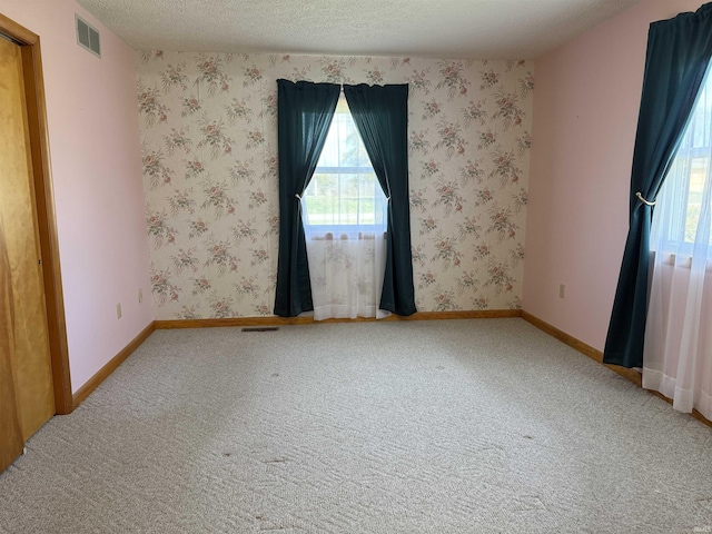 empty room with light carpet, wallpapered walls, and visible vents