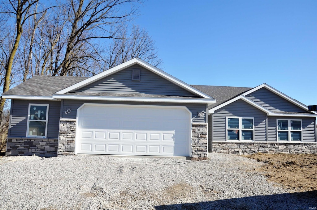 2016 Winesap Way, Kendallville, IN 46755 - view of front of house with stone siding, an attached garage, roof with shingles, and driveway