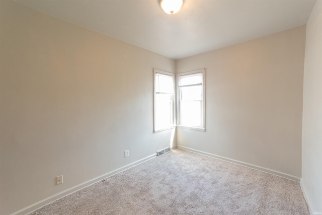 spare room with carpet floors, baseboards, and visible vents