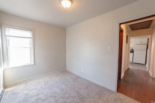 unfurnished room featuring carpet flooring, baseboards, and attic access