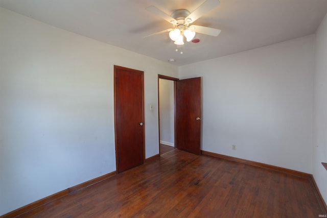 unfurnished room featuring baseboards, ceiling fan, and dark wood finished floors