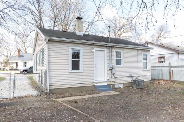 back of house featuring a chimney, entry steps, fence, and central AC