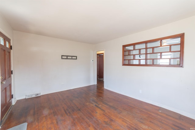 empty room featuring baseboards, visible vents, a healthy amount of sunlight, and hardwood / wood-style flooring
