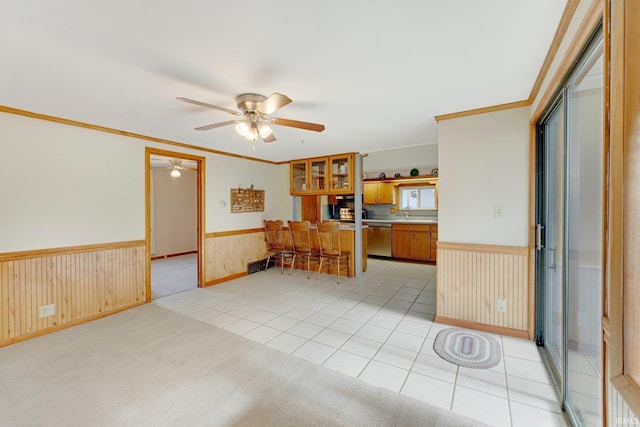 5540 N Willow Ave, Columbia City, IN 46725 - kitchen with stainless steel dishwasher, wooden walls, a ceiling fan, brown cabinetry, and wainscoting