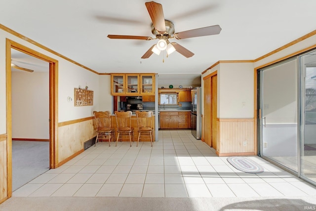 5540 N Willow Ave, Columbia City, IN 46725 - kitchen with crown molding, freestanding refrigerator, wainscoting, brown cabinetry, and visible vents