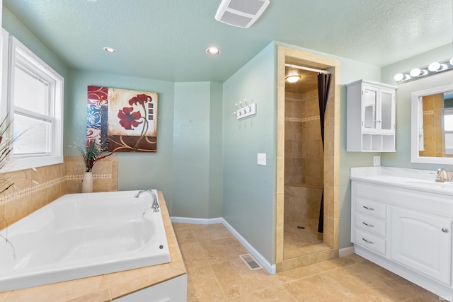 3323 Kiowa Ct, Fort Wayne, IN 46815 - bathroom featuring a textured ceiling, visible vents, plenty of natural light, vanity, and a garden tub