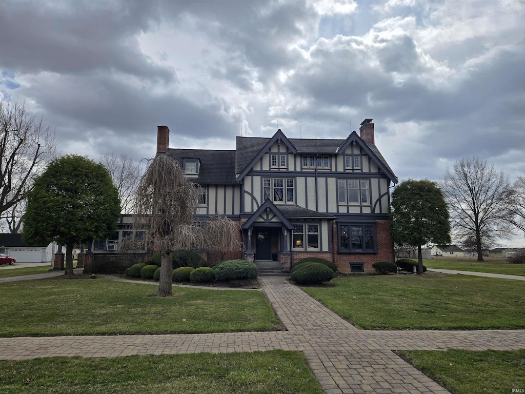 507 W Union St, Ligonier, IN 46767 - tudor-style house featuring a front lawn, a chimney, and brick siding