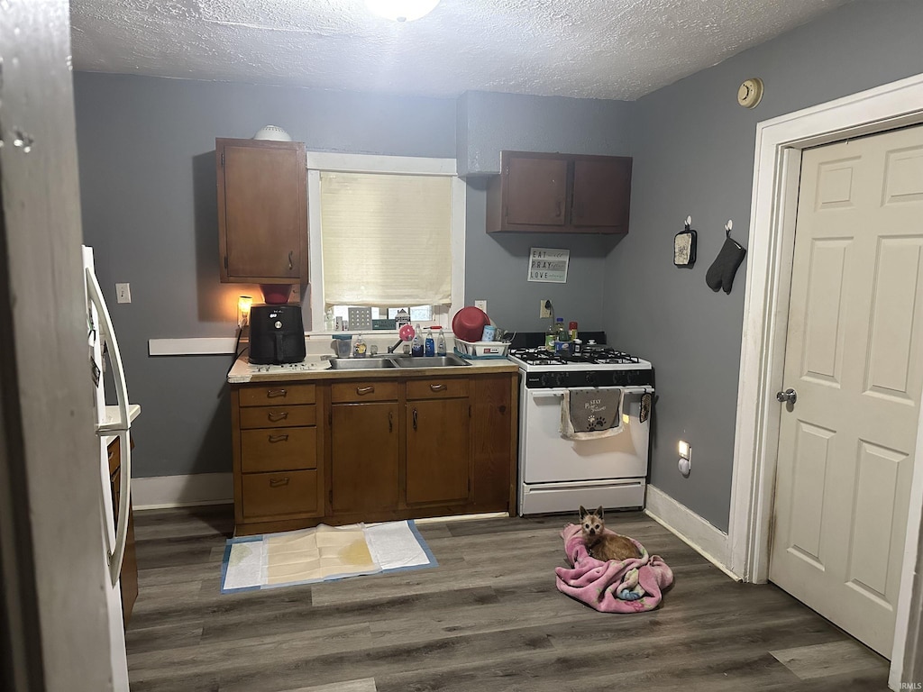 kitchen with white gas range, a sink, a textured ceiling, and dark wood finished floors