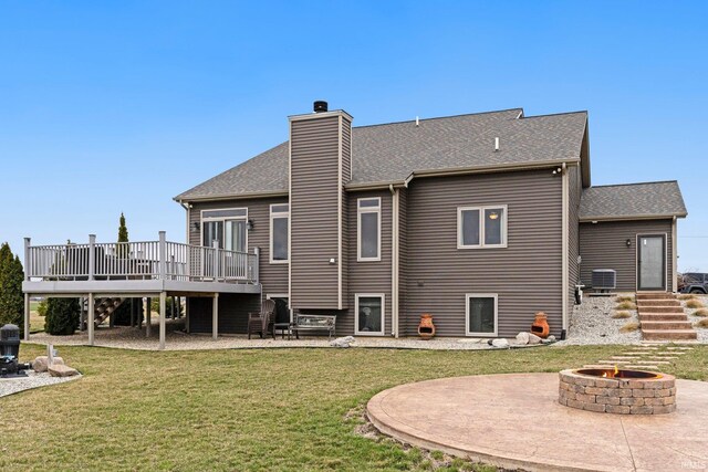 back of house featuring a patio area, an outdoor fire pit, a chimney, a deck, and a yard