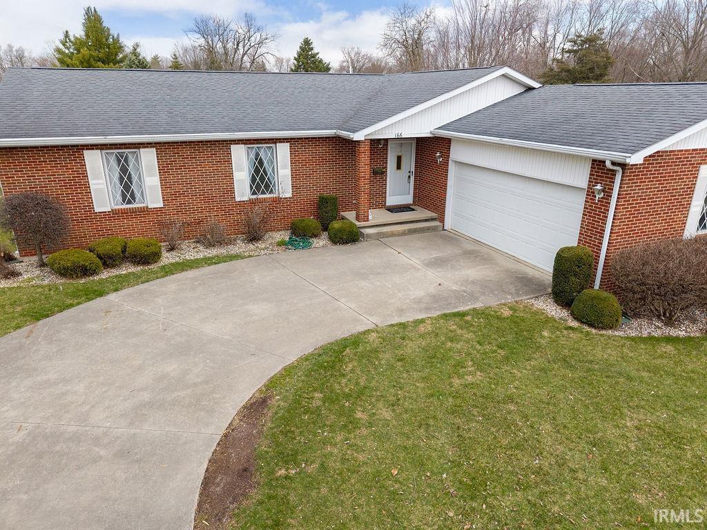 single story home with driveway, a front yard, brick siding, and roof with shingles