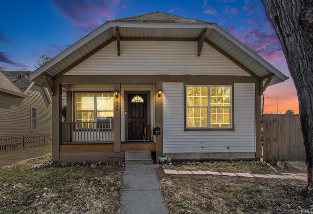 bungalow-style house with covered porch and fence