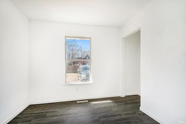 spare room with dark wood-style flooring and baseboards
