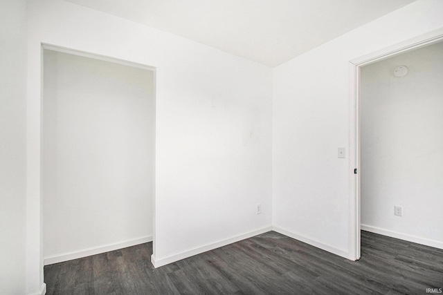 unfurnished room featuring baseboards and dark wood finished floors
