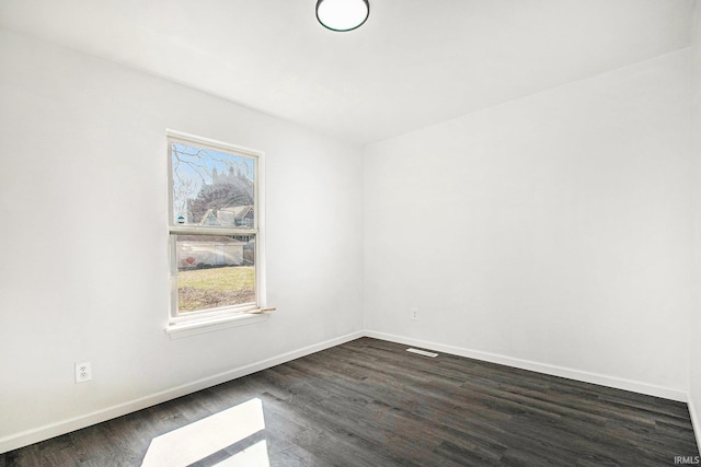 empty room with baseboards, visible vents, and dark wood-style flooring