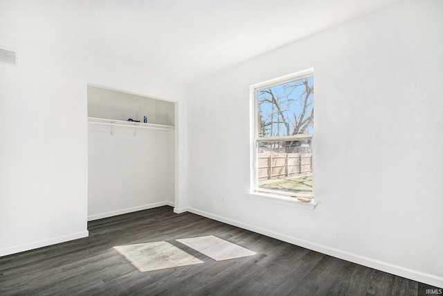 unfurnished bedroom featuring baseboards, a closet, and dark wood finished floors