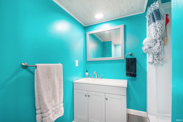 bathroom featuring vanity, recessed lighting, ornamental molding, baseboards, and wood finished floors
