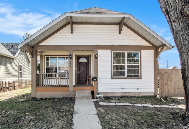 bungalow-style house with covered porch and fence